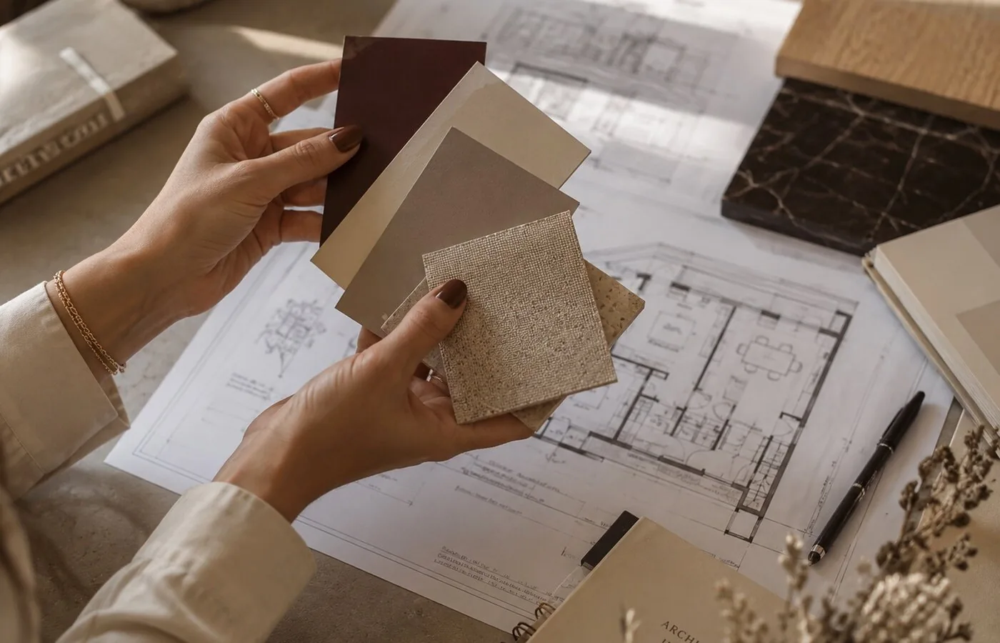 Mains tenant des échantillons de matières au-dessus de plans d'architecture